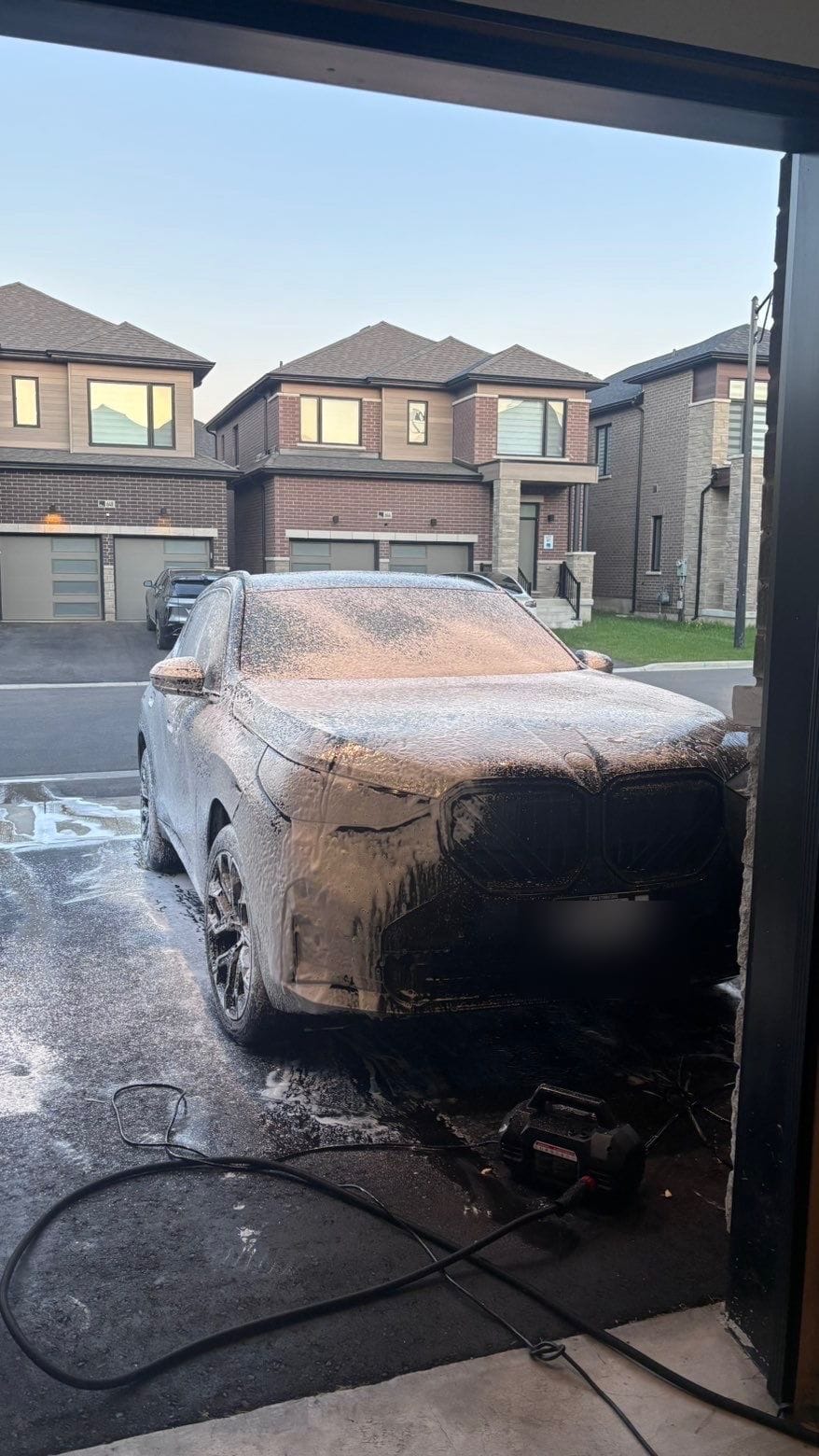Black BMW X5 covered in thick snow-foam during a Spotliss wash in Milton